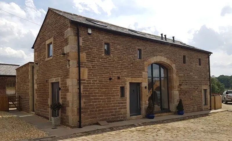 Stone barn conversion with dark framed arched window